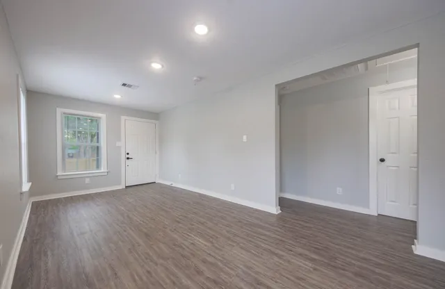 a view of an empty room with wooden floor and a window