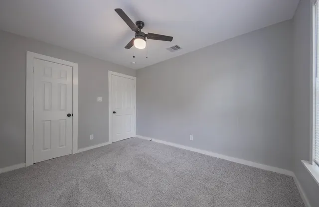 an empty room with a ceiling fan and carpet