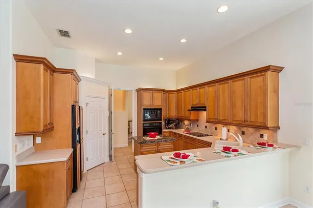 a view of kitchen with stainless steel appliances kitchen island granite countertop a refrigerator and a stove top oven