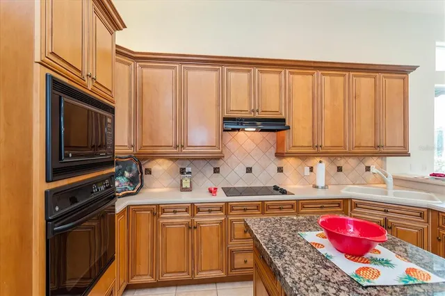 a kitchen with granite countertop lots of stainless steel appliances wooden cabinets and a sink