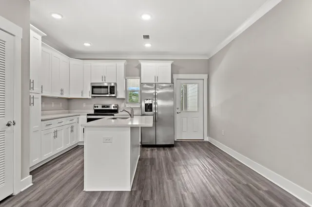 a kitchen with wooden floors white cabinets and stainless steel appliances