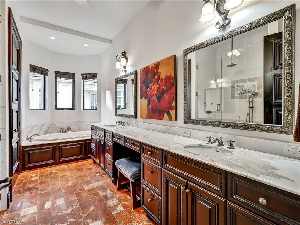 2535 Tarpon Road Naples, FL 34102 - Photo 25 of 50 Dual vanity with undermount sinks and marble countertops, rich wood cabinetry, a built-in garden tub, and decorative floor tiling