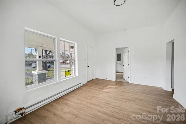 a view of an empty room with window and wooden floor