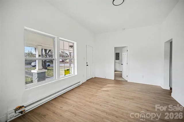 a view of an empty room with window and wooden floor