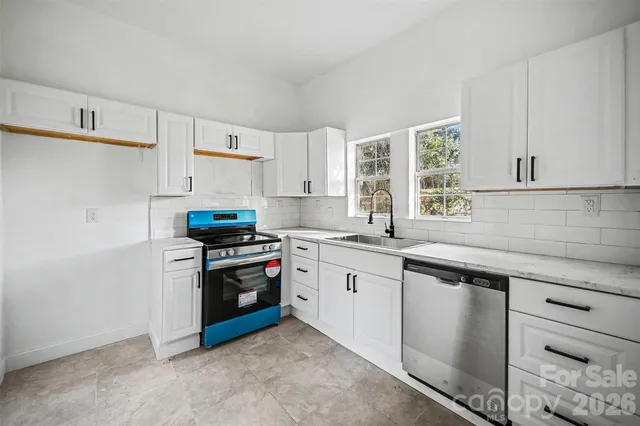 a kitchen with granite countertop white cabinets and stainless steel appliances