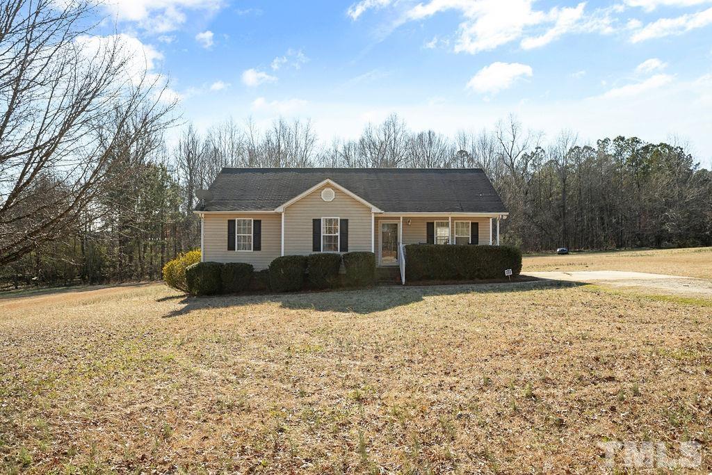 a front view of house with yard and trees in the background