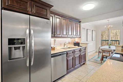 a kitchen with stainless steel appliances granite countertop a refrigerator a stove a sink and a dining table with white cabinets