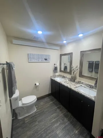 a bathroom with a granite countertop toilet a sink and a large mirror