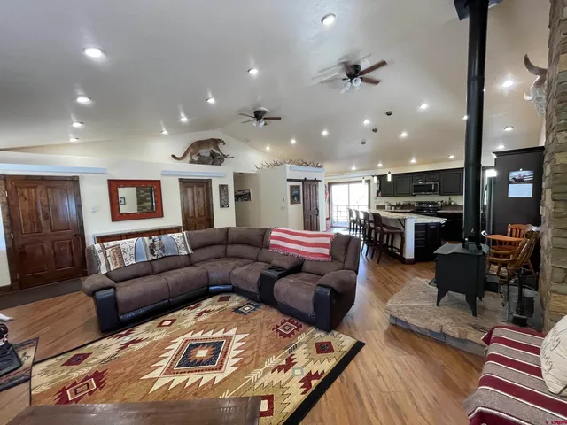 a living room with furniture kitchen view and a wooden floor