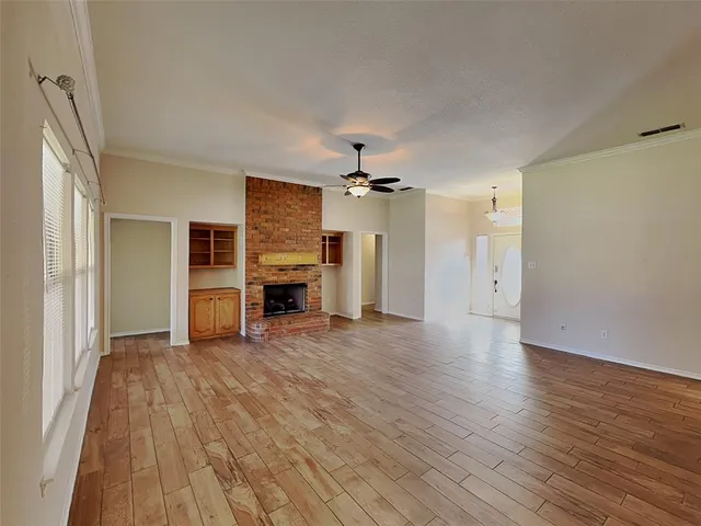 an empty room with wooden floor fireplace and windows