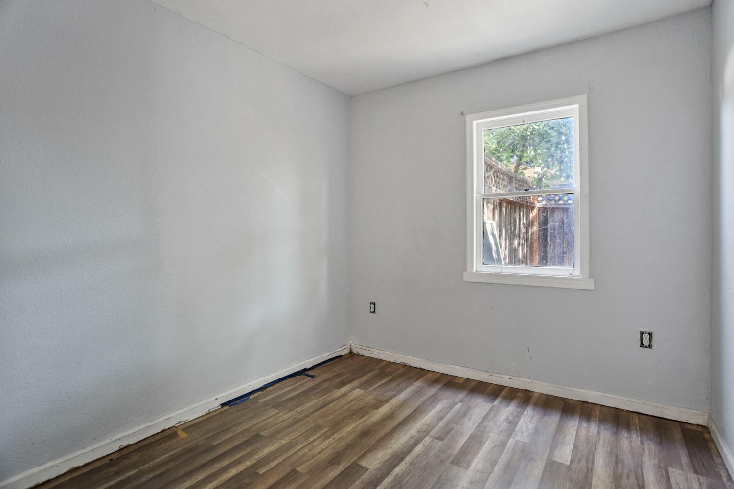 916 Elm Avenue Modesto, CA 95351 - Photo 44 of 52 Rear unit bedroom with closet storage, wood-look flooring, neutral finish, and access to adjoining hallway.