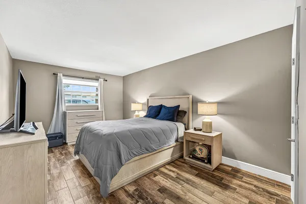 a bedroom with a bed a large window and flat screen tv