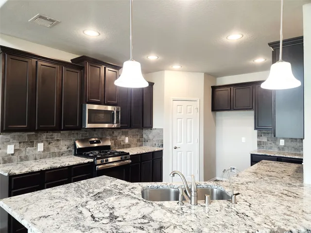 a kitchen with stainless steel appliances kitchen island granite countertop a sink stove and refrigerator