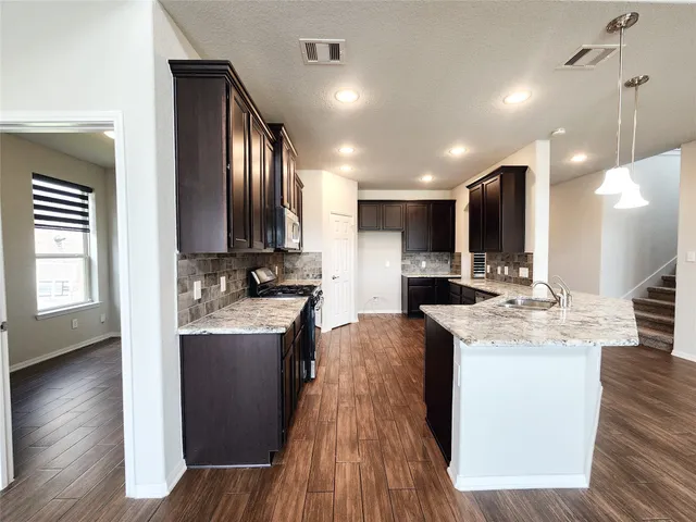 a kitchen with stainless steel appliances kitchen island granite countertop a sink stove and wooden floor