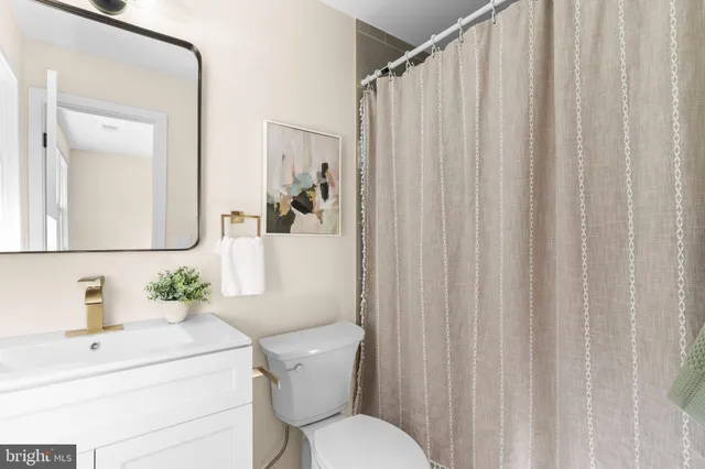 a bathroom with a sink a toilet and shower curtain