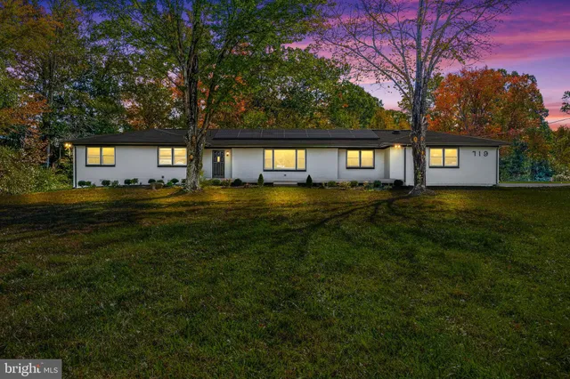 a front view of a house with a yard and trees