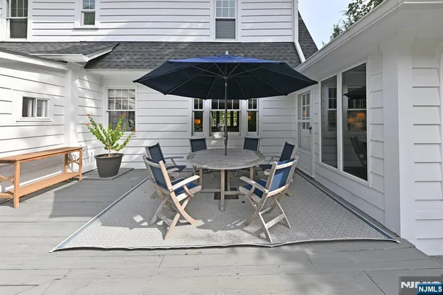 a view of a patio with table and chairs under an umbrella with a barbeque