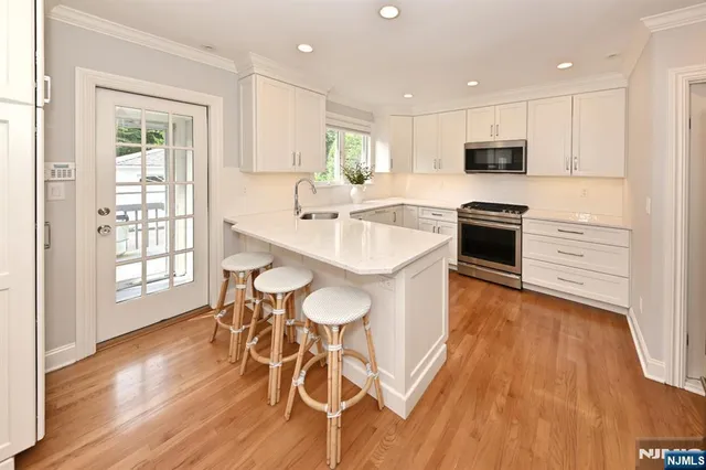 a large white kitchen with wooden floor and stainless steel appliances