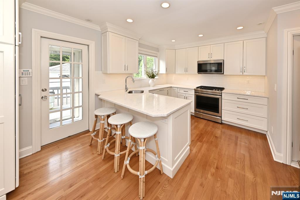 18 Tonawanda Road Glen Rock, NJ 07452 - Photo 9 of 37 a large white kitchen with wooden floor and stainless steel appliances