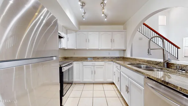 a kitchen with granite countertop a sink a stove top oven and cabinetry