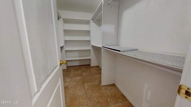 an empty room with a chandelier fan and windows