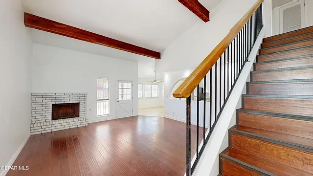 a view of an empty room with wooden floor fireplace and a window