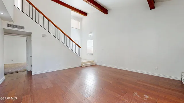 a view of an empty room with wooden floor and stairs