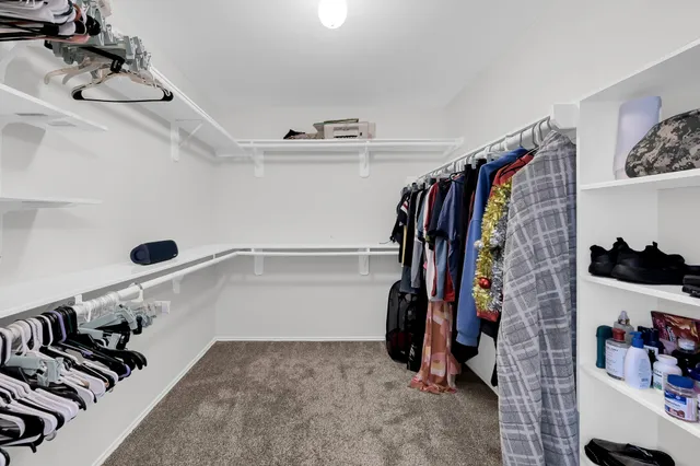a view of walk in closet with clothes and shoes