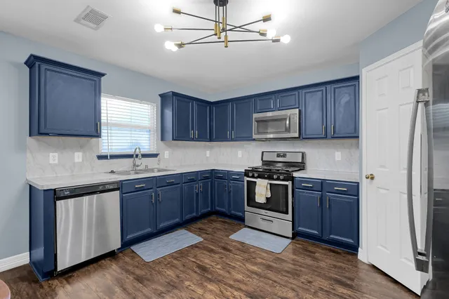 a kitchen with stainless steel appliances granite countertop wooden cabinets a stove a sink and a refrigerator