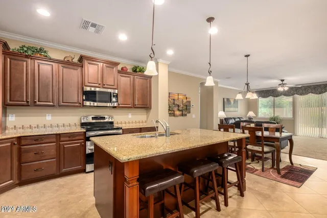 a kitchen with stainless steel appliances granite countertop a stove top oven a sink a dining table and chairs