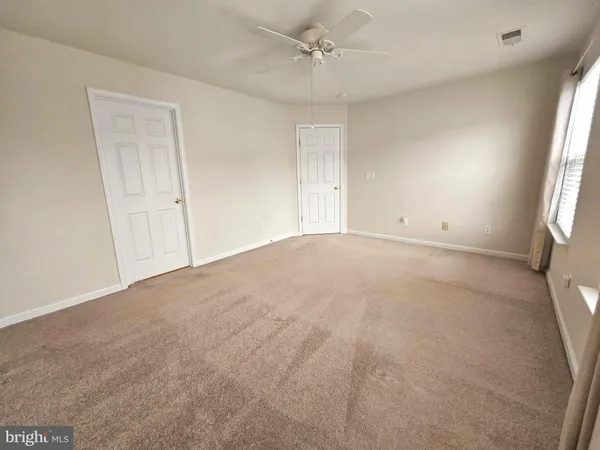 an empty room with windows and fan