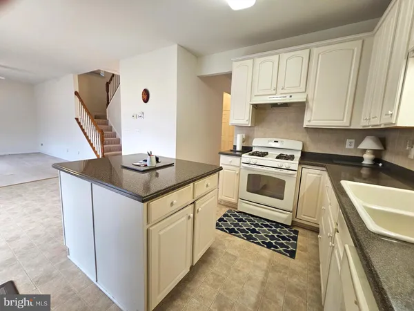 a kitchen with granite countertop a sink a stove and cabinets