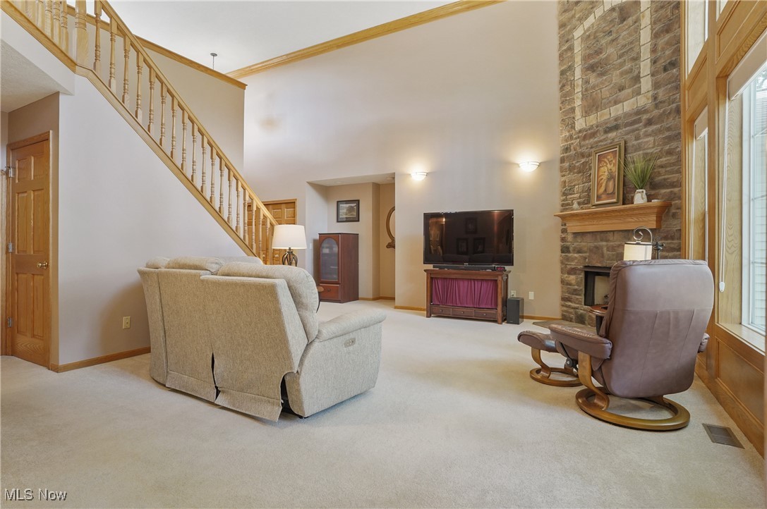 4265 Ridge Crest Drive Akron, OH 44321 - Photo 13 of 49 Carpeted living room with a towering ceiling, stairway, a stone fireplace, and ornamental molding