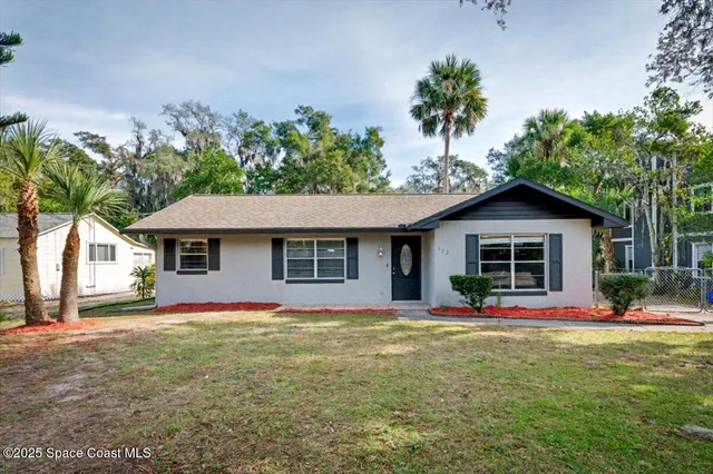 a front view of house with yard and trees around