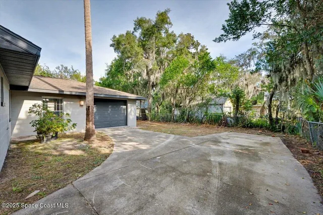 a view of a house with a yard and potted plants