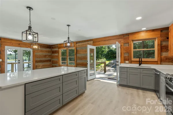 a large kitchen with kitchen island a large window a sink and stainless steel appliances