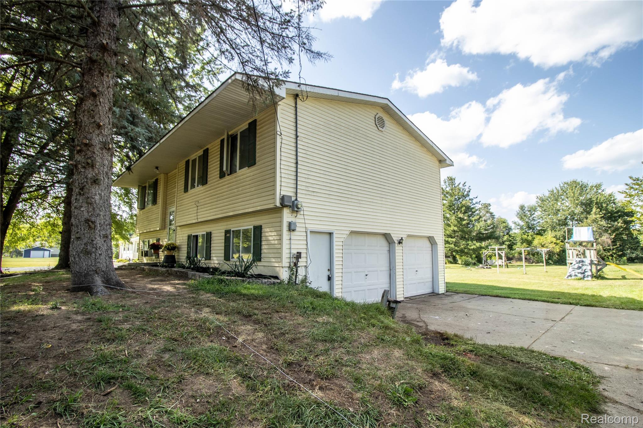 Two-story exterior with light-toned siding, dark shutters, and a two-car garage