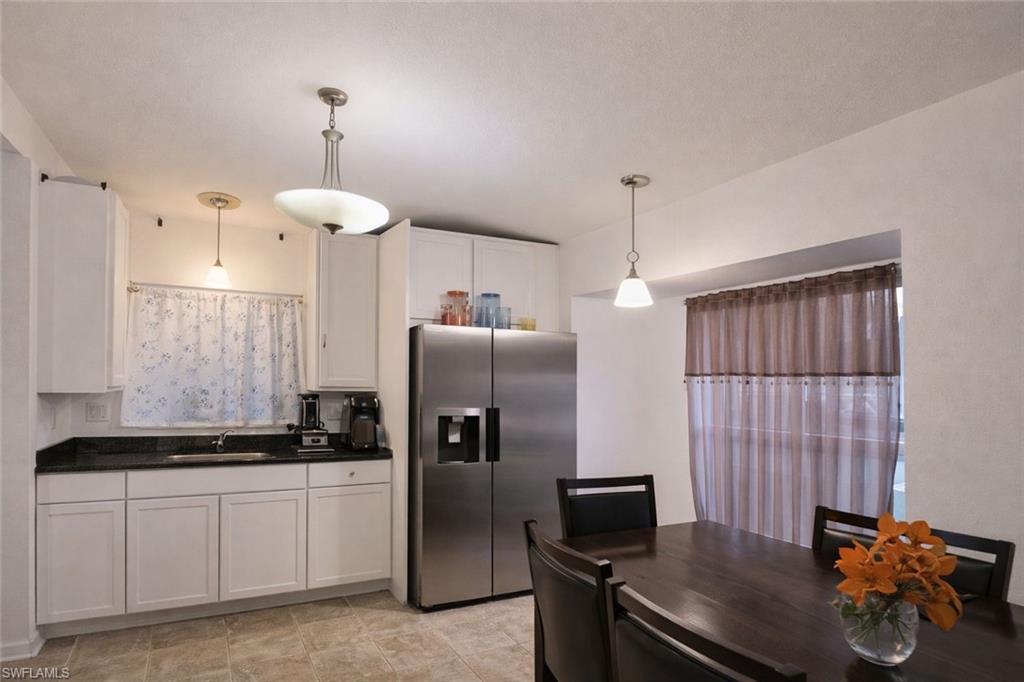 2275 Robin Drive Naples, FL 34117 - Photo 6 of 15 Kitchen with stainless steel refrigerator with ice dispenser, white cabinetry, and decorative light fixtures