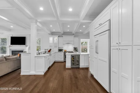 a large white kitchen with stainless steel appliances granite countertop lots of counter top space and wooden floor