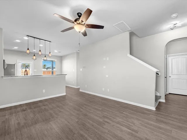 an empty room with wooden floor and a ceiling fan