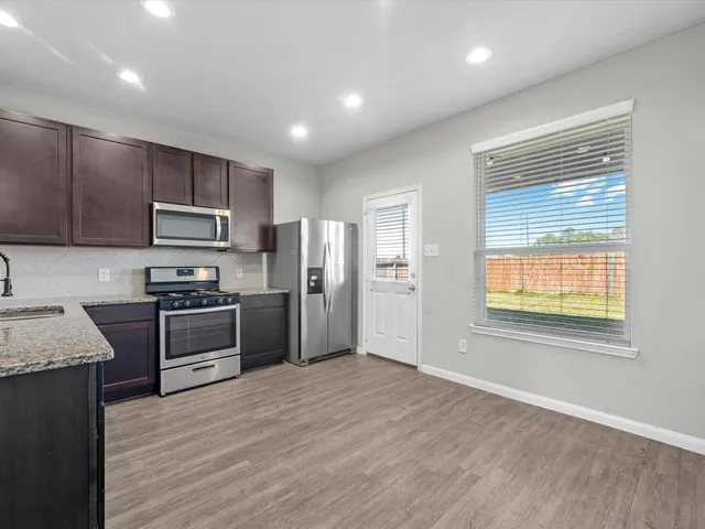 a kitchen with granite countertop stainless steel appliances cabinets a sink and a window