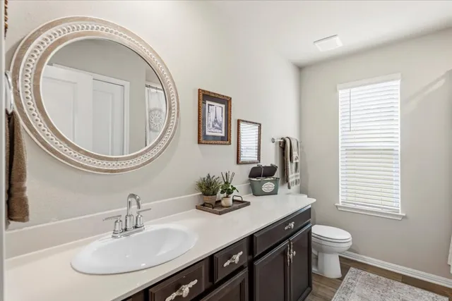 a bathroom with a granite countertop toilet a sink and a mirror