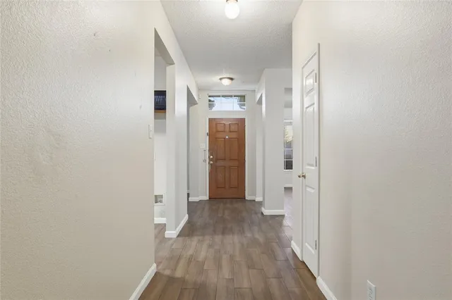 a view of a hallway with wooden floor and a bathroom