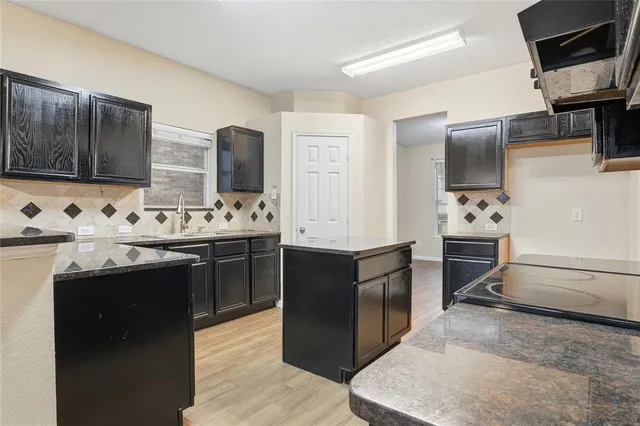 a kitchen with stainless steel appliances kitchen island granite countertop a sink stove and refrigerator