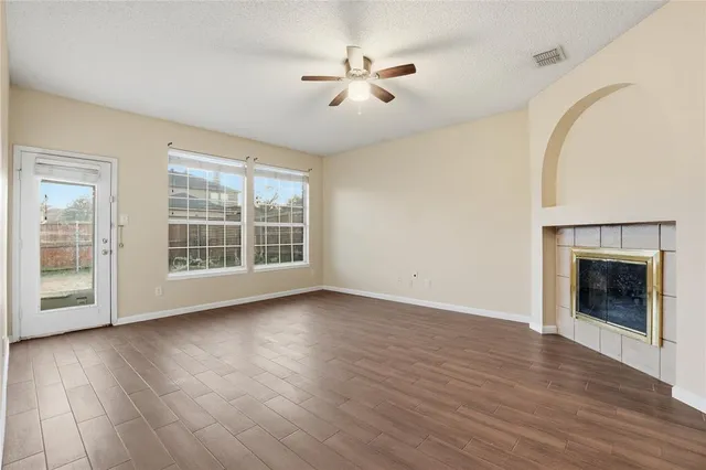 a view of an empty room with wooden floor fireplace and a window
