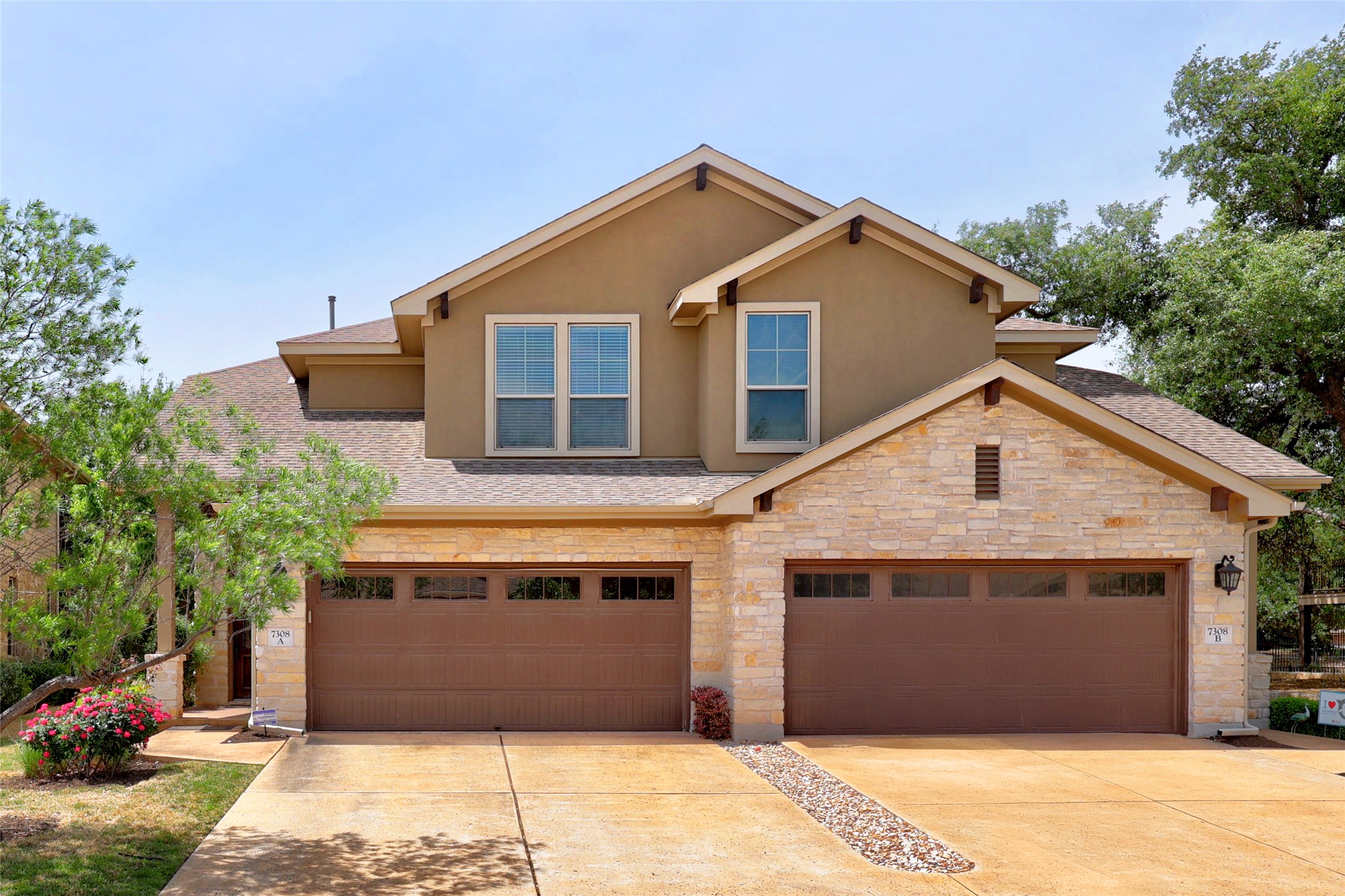 The property features a stucco and stone exterior, a brown roof, and two brown garage doors