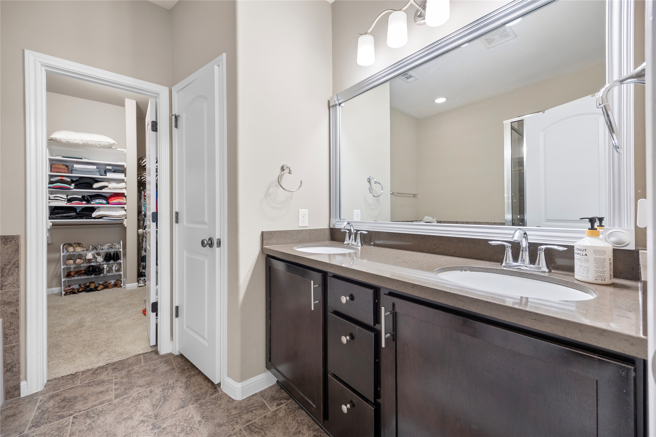 7308 Bandera Ranch Trail, Unit A Austin, TX 78750 - Photo 13 of 27 Bathroom featuring a dual vanity with a dark wood cabinet and light-colored countertop, and a large mirror with a decorative frame