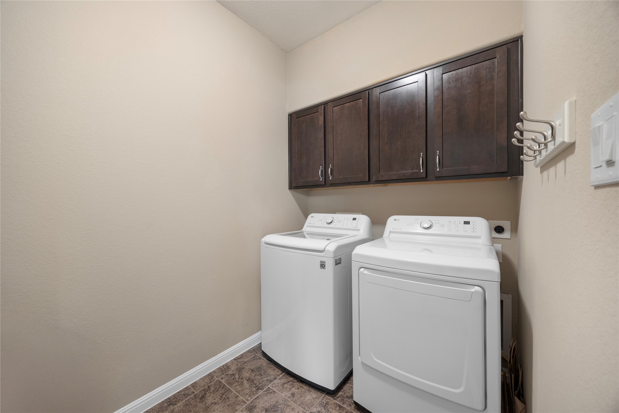 7308 Bandera Ranch Trail, Unit A Austin, TX 78750 - Photo 15 of 27 Laundry room featuring overhead dark wood cabinetry, a tiled floor, and neutral wall paint