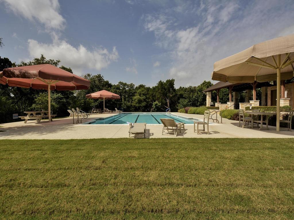 7308 Bandera Ranch Trail, Unit A Austin, TX 78750 - Photo 26 of 27 A spacious outdoor pool area featuring a rectangular pool, surrounded by a paved deck, and a lush green lawn