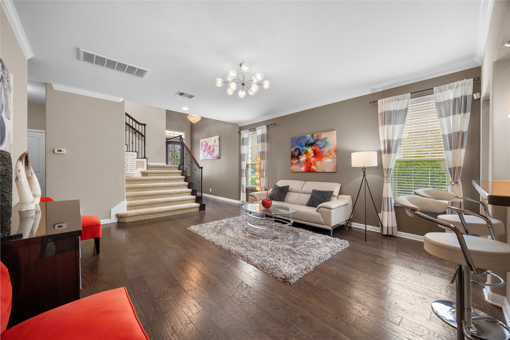 7308 Bandera Ranch Trail, Unit A Austin, TX 78750 - Photo 5 of 27 Inviting living area featuring rich hardwood floors, a carpeted staircase with a dark banister, and a contemporary chandelier